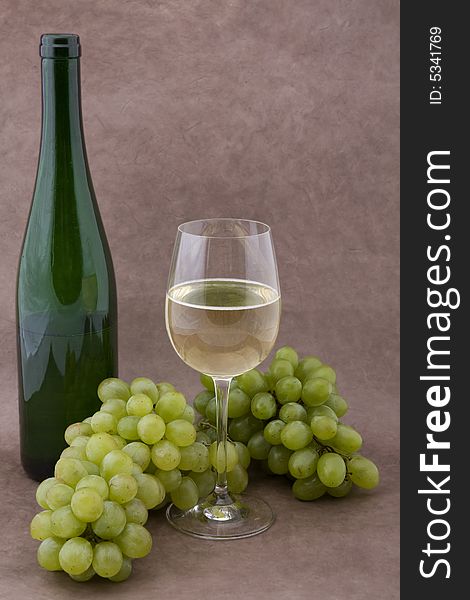 White wine with bottle, glasses and grapes against a background