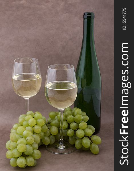 White wine with bottle, glasses and grapes against a background