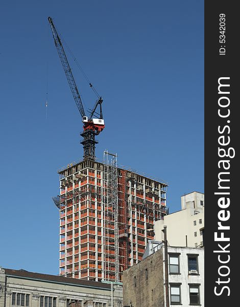 Crane on top of a new high rise building being constructed in a city. Crane on top of a new high rise building being constructed in a city.