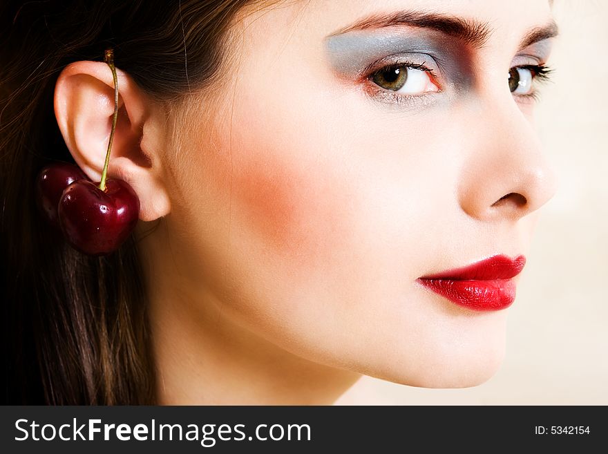 Beautiful young woman in evening make-up with cherry