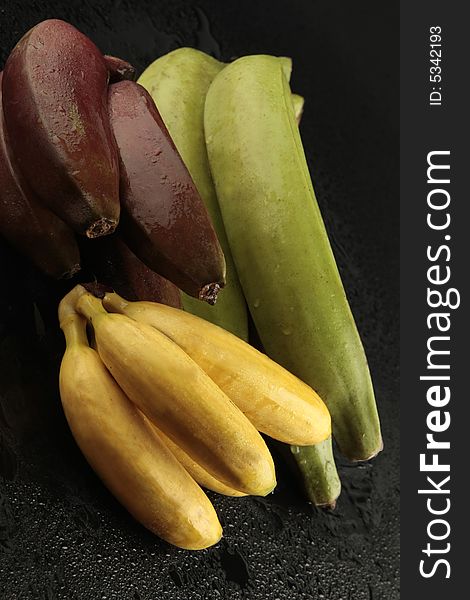 Group of bananas on black background with water drops