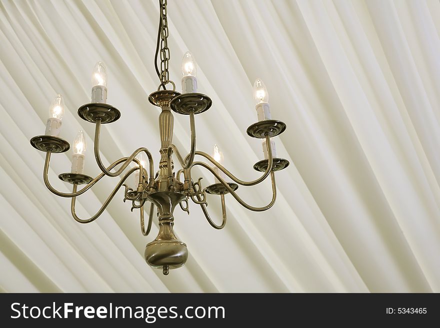 Chandelier hanging in a marquee under cream silk. Chandelier hanging in a marquee under cream silk