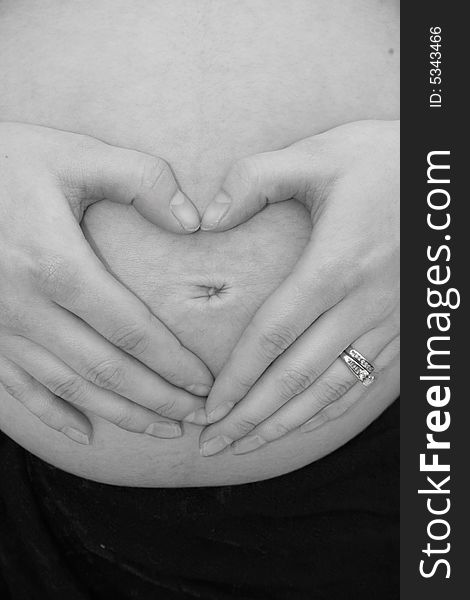 Hands forming heart on pregnant belly. Hands forming heart on pregnant belly