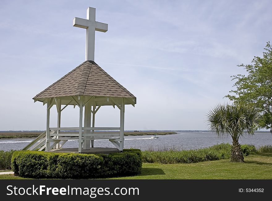 A gazebo on the shore of a wetland marsh with a cross on the roof. A gazebo on the shore of a wetland marsh with a cross on the roof