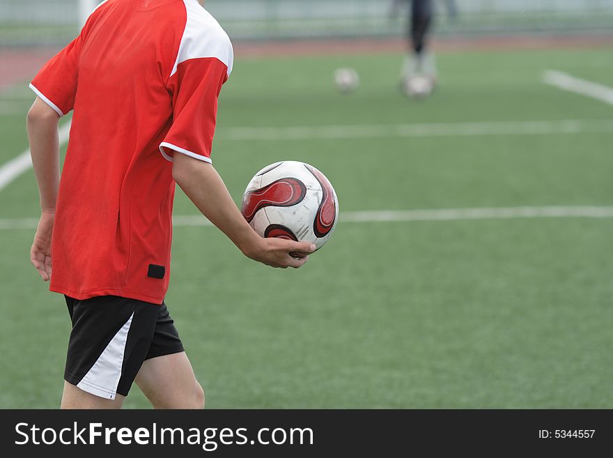 The football player runs in on a field with a ball in a hand