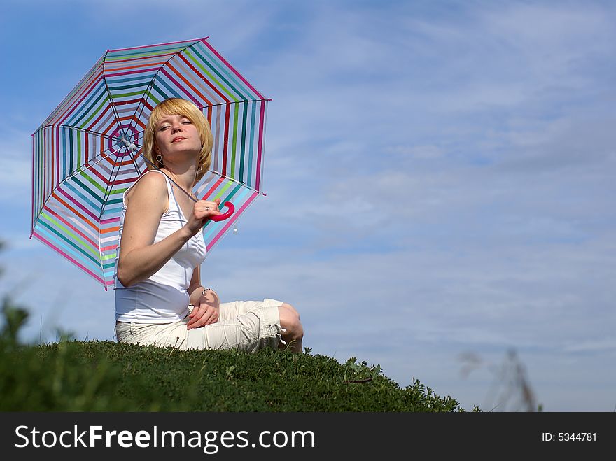 Young charming girl with umbrella against blue sky