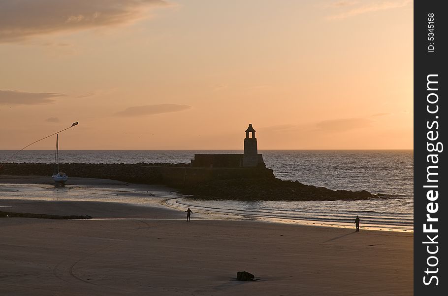 A lighthouse on the beach as sunsets