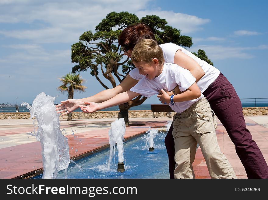 Mother and the son play and have fun at a fountain