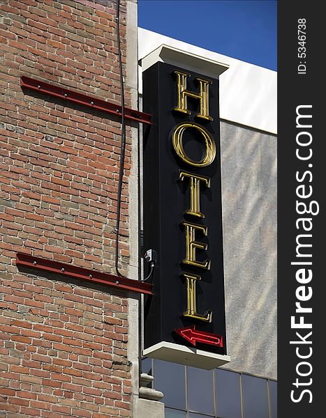 A neon sign for a hotel sticks out of a corner building. A neon sign for a hotel sticks out of a corner building.