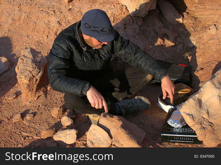 A camping man checks his dinner cooking on a gas stove. A camping man checks his dinner cooking on a gas stove