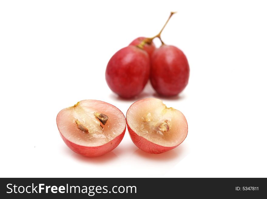 Grape sliced into two with a string of grapes over white background.