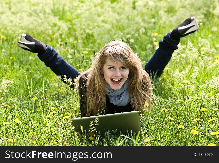 Nice young model with laptop on green grass background