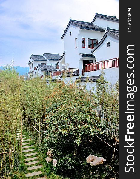 Chinese traditional house which is surrounded by bamboo. there is a litte way winding from the bamboo forest.