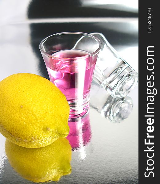 Cherry cocktail shot with a empty glass and a lemon on a silver background. Cherry cocktail shot with a empty glass and a lemon on a silver background