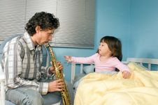 A Father Playing Saxophone For Daughter In Bed Royalty Free Stock Image