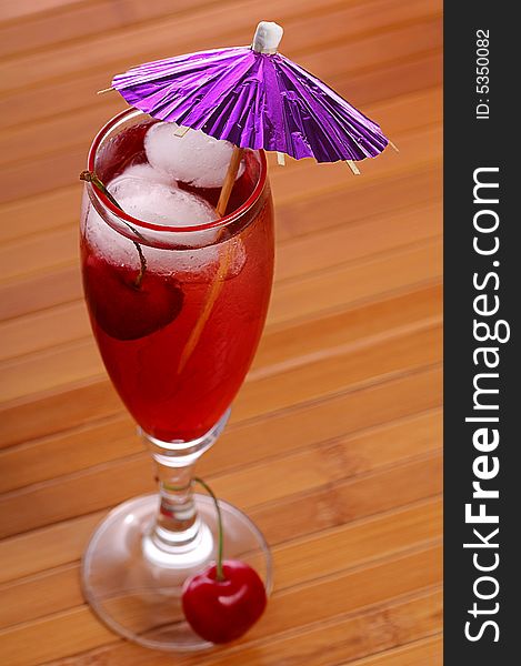 A red cocktail in a glass with cherry and ice. A red cocktail in a glass with cherry and ice