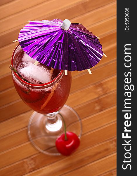 A red cocktail in a glass with cherry and ice. A red cocktail in a glass with cherry and ice