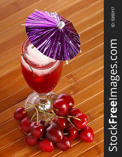 A red cocktail in a glass with cherry and ice. A red cocktail in a glass with cherry and ice