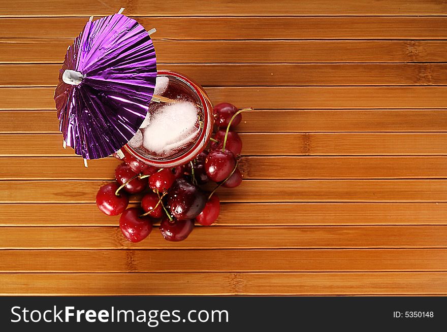 A red cocktail in a glass with cherry and ice. A red cocktail in a glass with cherry and ice