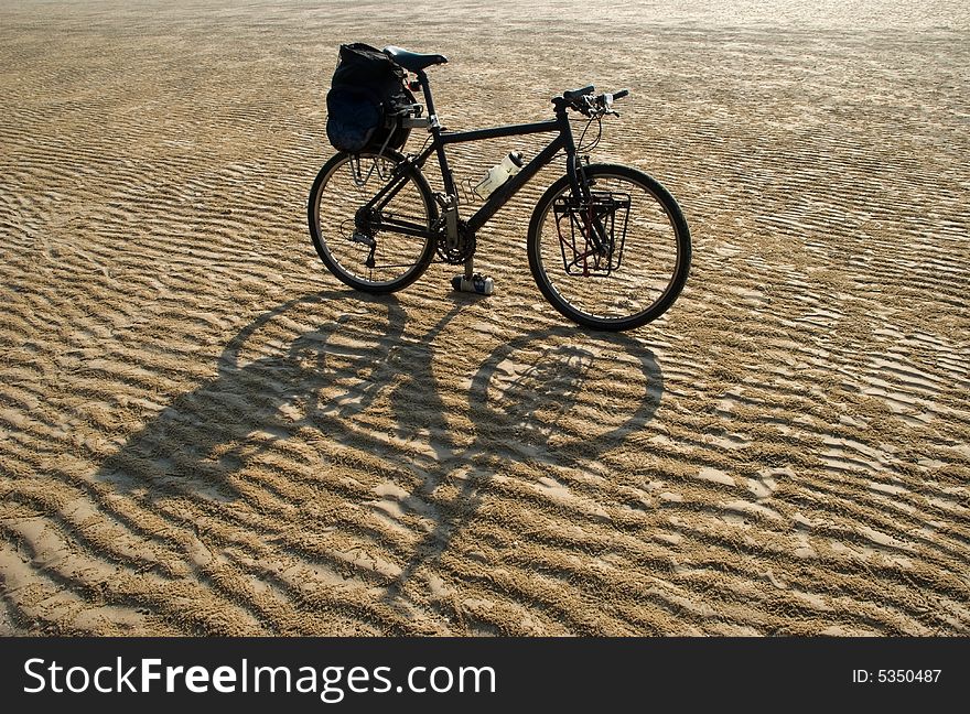 A black mountain bike in a desert. A black mountain bike in a desert