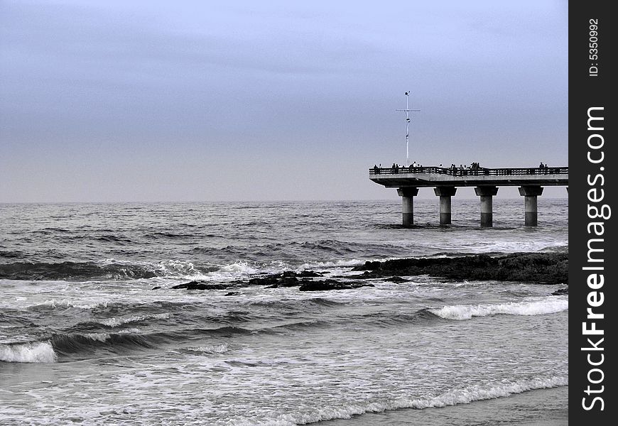 Black and white pier in stormy sea with blue sky. Black and white pier in stormy sea with blue sky