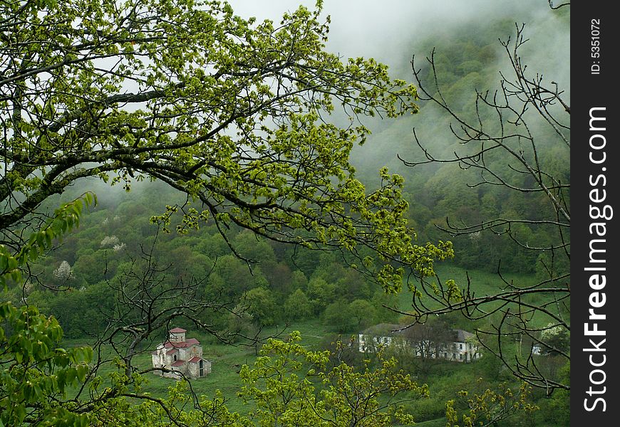 A view of an old monastery in the morning gauze seen through the branches