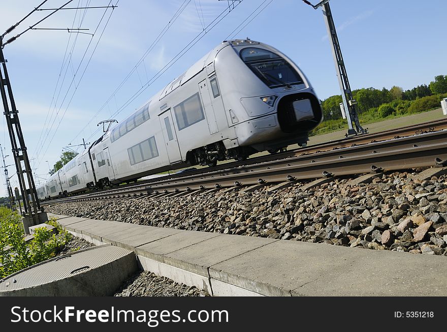 High-speed commuter-train on the move, surrounded by countryside and blue-sky. High-speed commuter-train on the move, surrounded by countryside and blue-sky