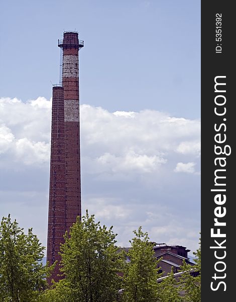 White and red chimney of factory against the sky and clouds. White and red chimney of factory against the sky and clouds.