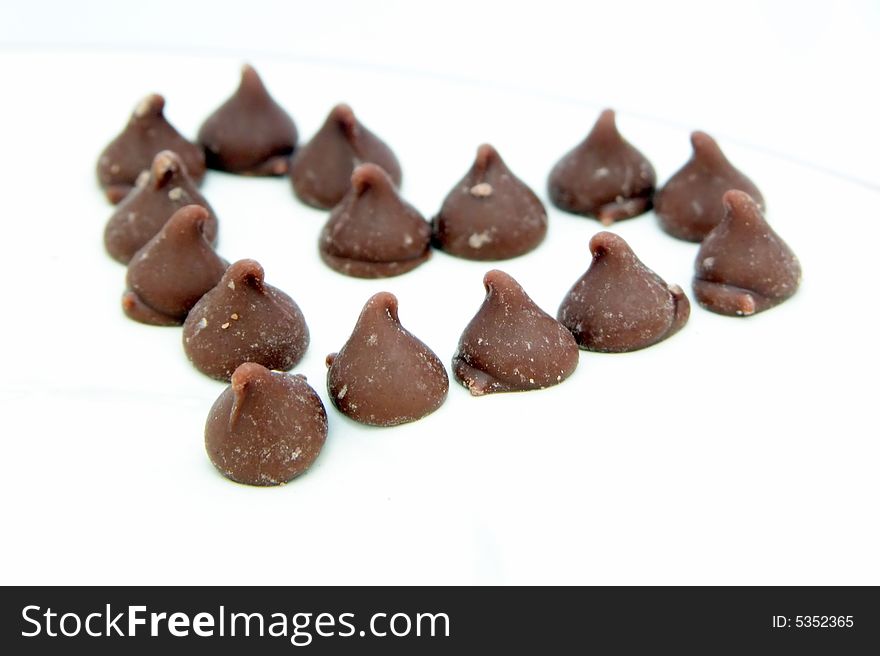 Tempting rich chocolates drops in a heart shape arrangement - isolated on white with copy space. Tempting rich chocolates drops in a heart shape arrangement - isolated on white with copy space.