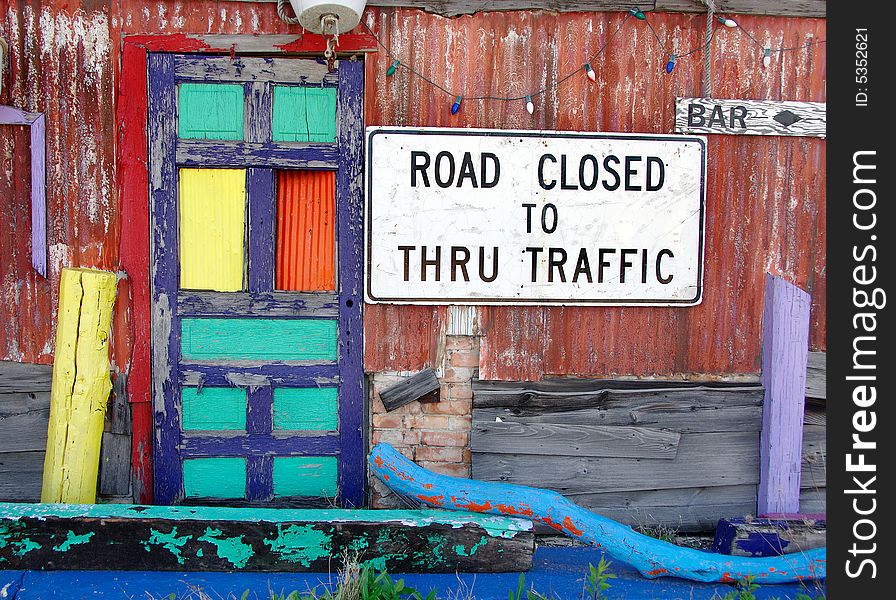 Abandoned structure painted in bright colors with an old road sign. Abandoned structure painted in bright colors with an old road sign.