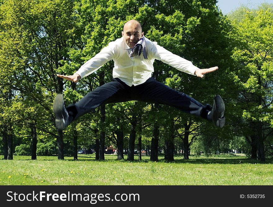 Businessman jumping in the park. Businessman jumping in the park.
