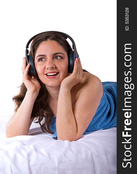 A beautiful girl, lying wrapped in a blue towel, wearing headphones, enjoying the music. A beautiful girl, lying wrapped in a blue towel, wearing headphones, enjoying the music