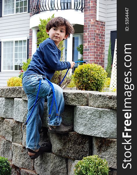 Adorable little boy top roping and climbing a stone garden wall using bungee cords as climbing rope. Vertically framed shot. Adorable little boy top roping and climbing a stone garden wall using bungee cords as climbing rope. Vertically framed shot.