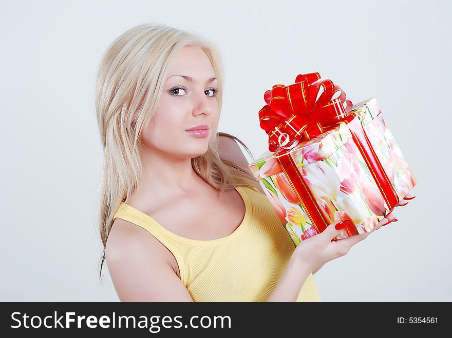 Smiling blond dressed in yellow shirt with big gift box in hands. Smiling blond dressed in yellow shirt with big gift box in hands