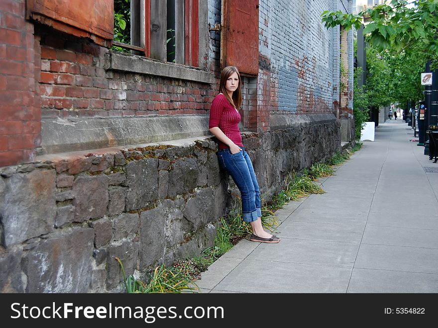Outdoor shot of a teenage girl with her hands in her pockets leaning against a brick and stone wall. Outdoor shot of a teenage girl with her hands in her pockets leaning against a brick and stone wall.