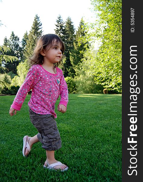 Adorable brown-haired girl running in lush green grass on a summer day. Vertically framed shot. Girl is running towards the camera. Adorable brown-haired girl running in lush green grass on a summer day. Vertically framed shot. Girl is running towards the camera.