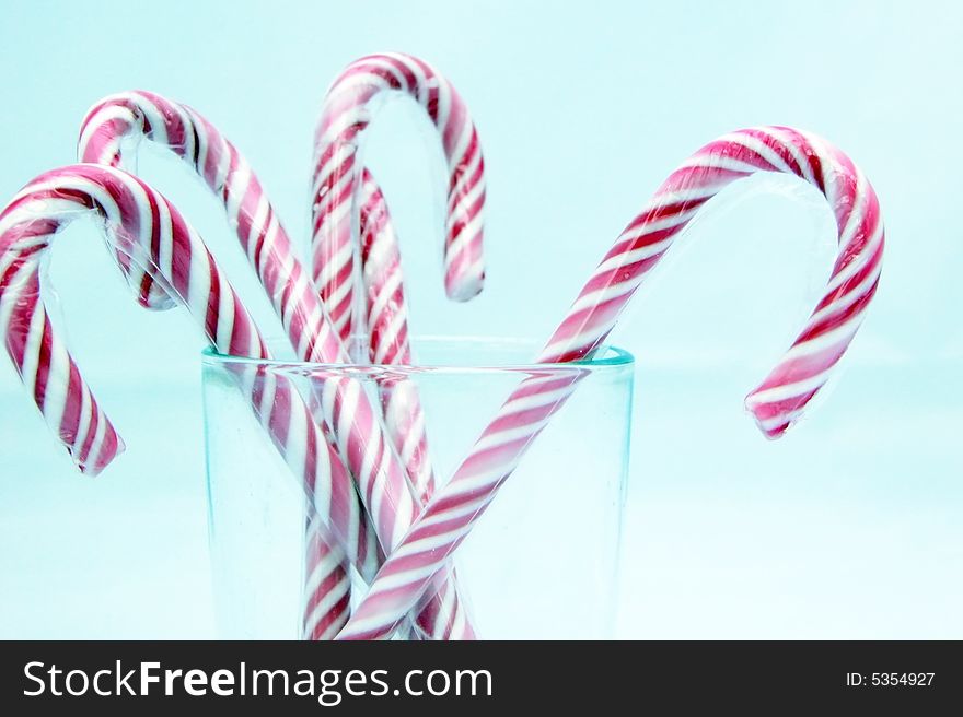 Red and white striped candy canes - or sticks of rock in the UK - isolated on a light blue background. Red and white striped candy canes - or sticks of rock in the UK - isolated on a light blue background.