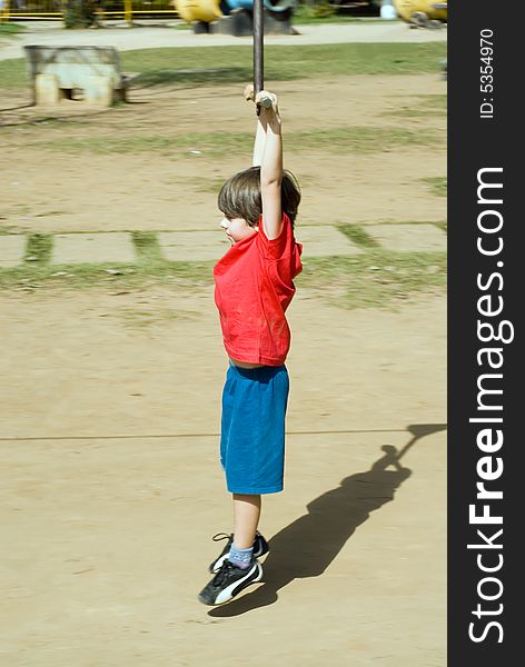 Young boy hanging from a zip-line as he rides it. Young boy hanging from a zip-line as he rides it.