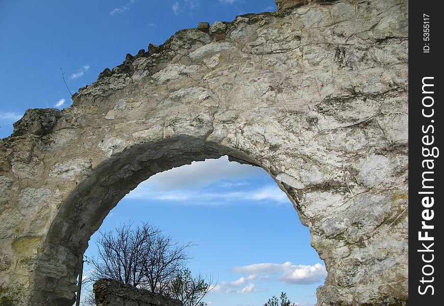 Arch of wall of an old building and  blue sky with clouds