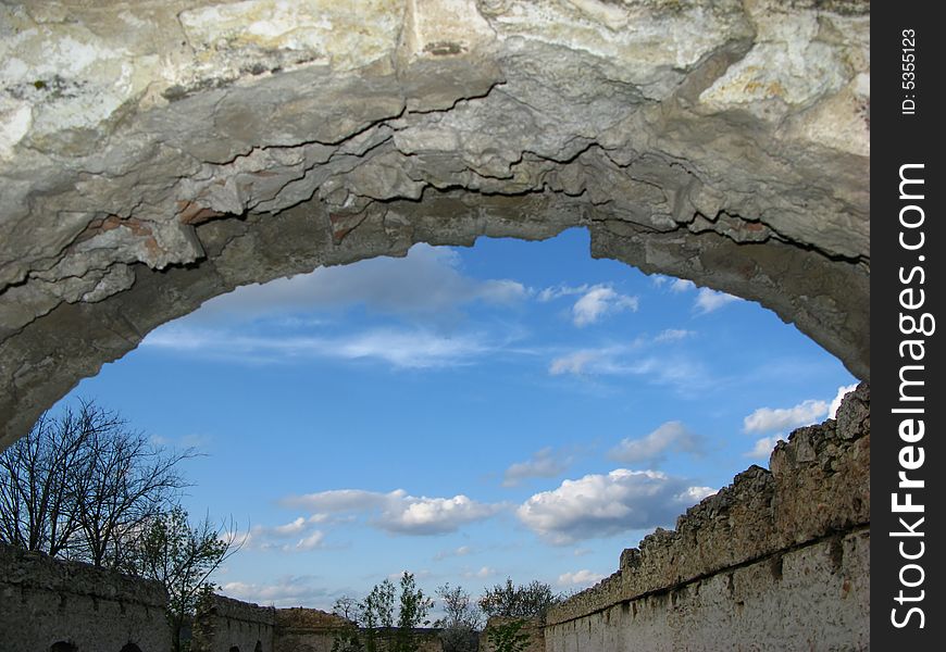 Arch of wall of an old building and blue sky with clouds