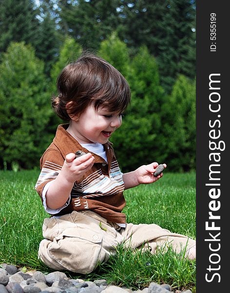 Adorable little boy playing in the grass outside on a hot summer day. Vertically framed shot. Adorable little boy playing in the grass outside on a hot summer day. Vertically framed shot.