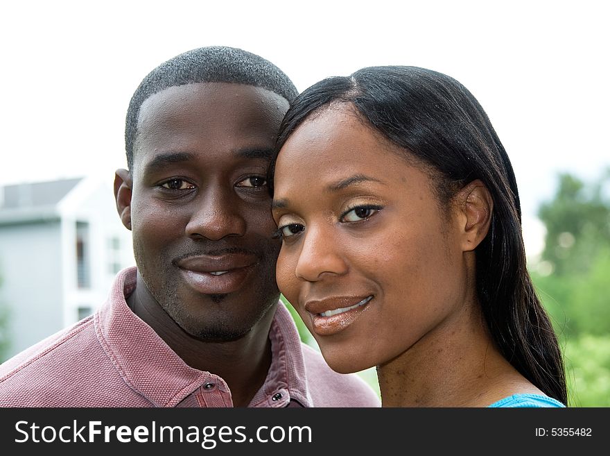 Attractive smiling young couple, looking at the camera, in a close-up embrace. Horizontally framed portrait shot. Attractive smiling young couple, looking at the camera, in a close-up embrace. Horizontally framed portrait shot.