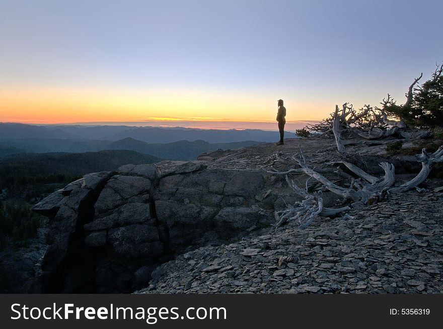 Woman watching the sunset from a rock bluff. Woman watching the sunset from a rock bluff