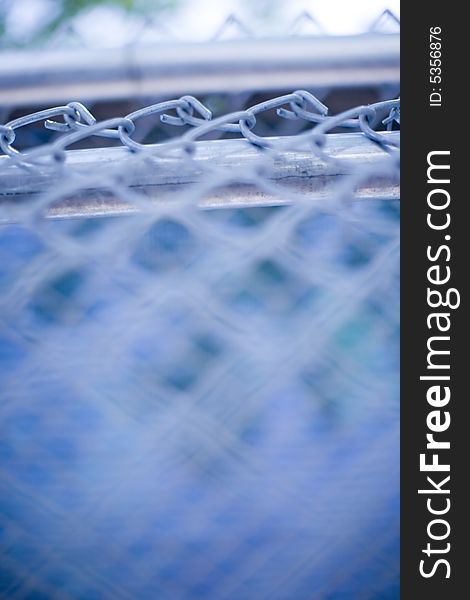 Close-up of a blue fence outside with a blurred foreground and chain link in focus. Close-up of a blue fence outside with a blurred foreground and chain link in focus