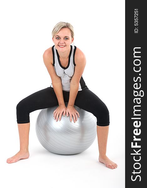 Blond woman in gym outfit exercising with a pilates ball isolated on white