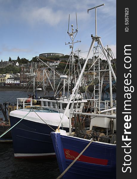 Oban harbour with fishing boats at the quayside and with McCaigs tower in the distance. Oban harbour with fishing boats at the quayside and with McCaigs tower in the distance