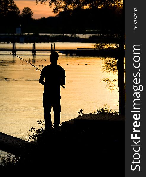 Man fishing on shoreline at dusk during a sunset. Man fishing on shoreline at dusk during a sunset.