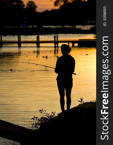 Women fishing on shoreline at dusk during a sunrise. Women fishing on shoreline at dusk during a sunrise.