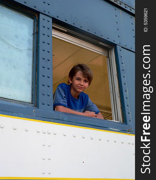 Boy in blue t-shirt in blue train leaning out the window; very handsome. Boy in blue t-shirt in blue train leaning out the window; very handsome