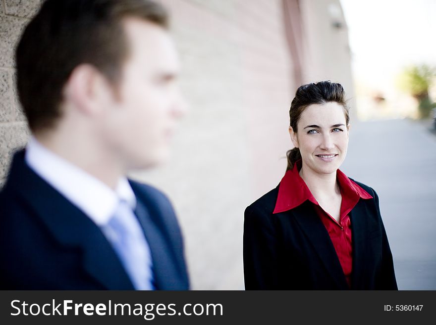 Attractive businesswoman and businessman standing looking at each other wearing formal business wear. Attractive businesswoman and businessman standing looking at each other wearing formal business wear